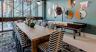 Unique dining or game room at Trio Apartments in Chicago with a shuffleboard table, long communal table, and stylish decor
