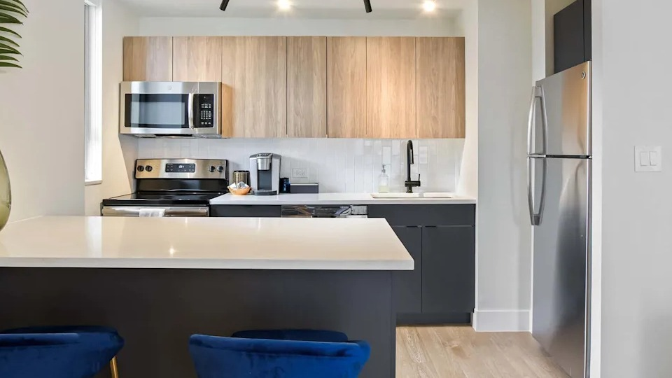 Contemporary kitchen featuring two-tone wood and dark cabinets, stainless steel appliances, and a convenient breakfast bar at Two East Oak in Chicago