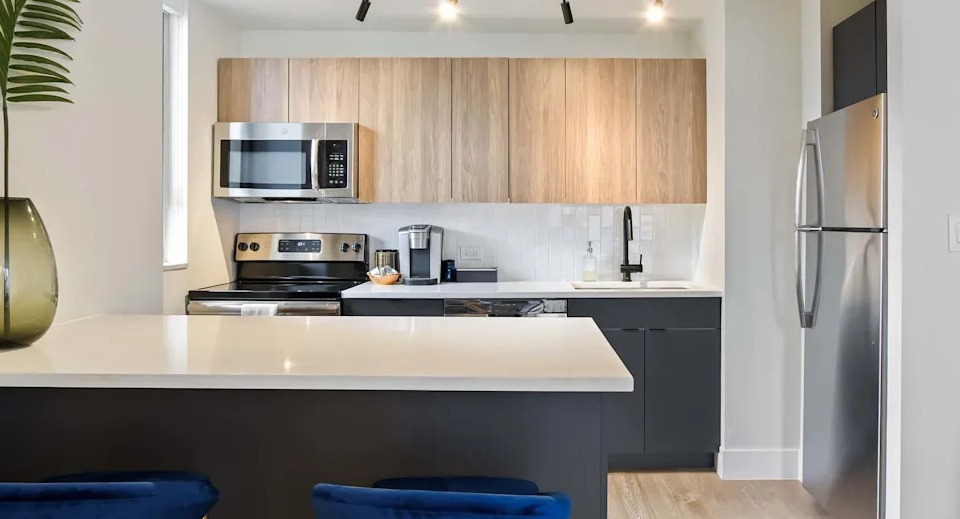 Contemporary kitchen featuring two-tone wood and dark cabinets, stainless steel appliances, and a convenient breakfast bar at Two East Oak in Chicago