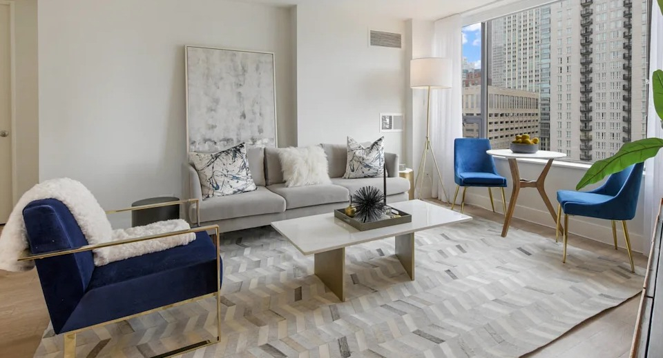 Bright and airy living area with a plush sofa, modern chairs, elegant decor, and large windows at Two East Oak in Chicago