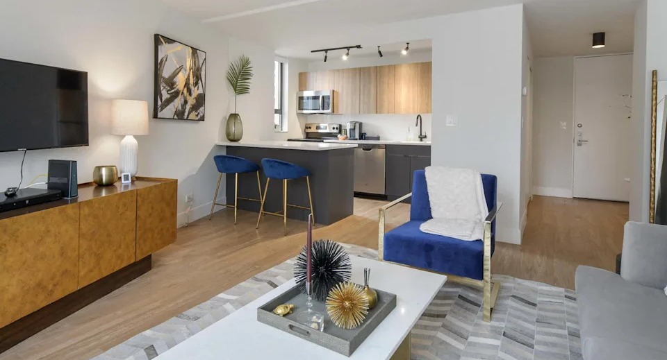Open-concept living room flowing into a modern kitchen with an island, dark cabinetry, and sleek appliances at Two East Oak in Chicago