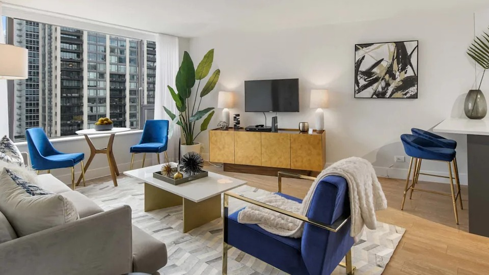 Vibrant living room with a comfortable sofa, blue accent chairs, and stylish decor, offering views of the city at Two East Oak in Chicago