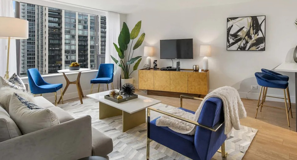 Vibrant living room with a comfortable sofa, blue accent chairs, and stylish decor, offering views of the city at Two East Oak in Chicago