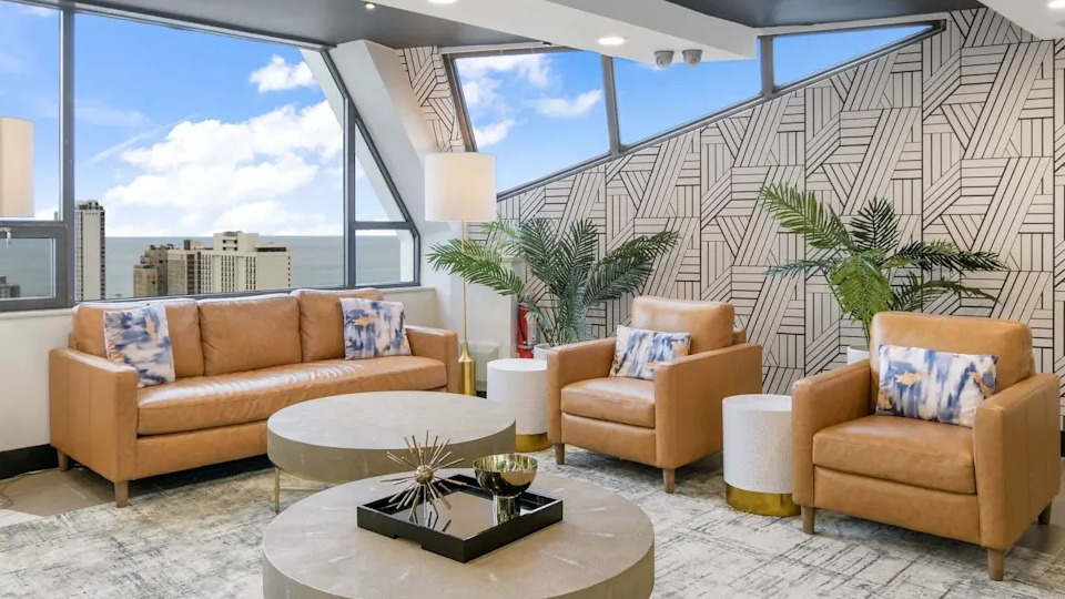 Stylish resident lounge with leather sofas, comfortable chairs, and large windows offering beautiful lake views at Two East Oak in Chicago
