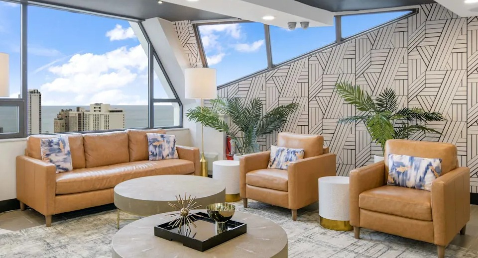 Stylish resident lounge with leather sofas, comfortable chairs, and large windows offering beautiful lake views at Two East Oak in Chicago
