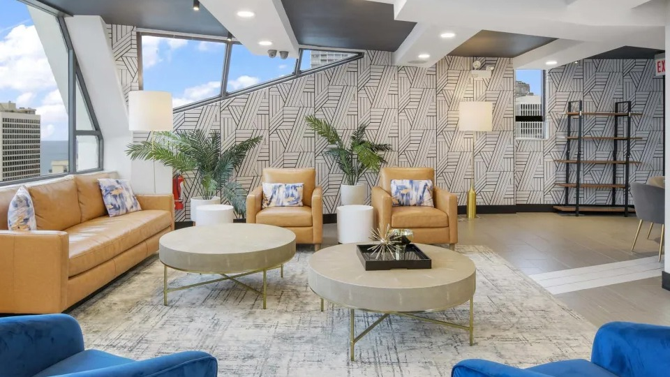 Modern resident lounge with comfortable seating, decorative wallpaper, and a cozy reading corner at Two East Oak in Chicago