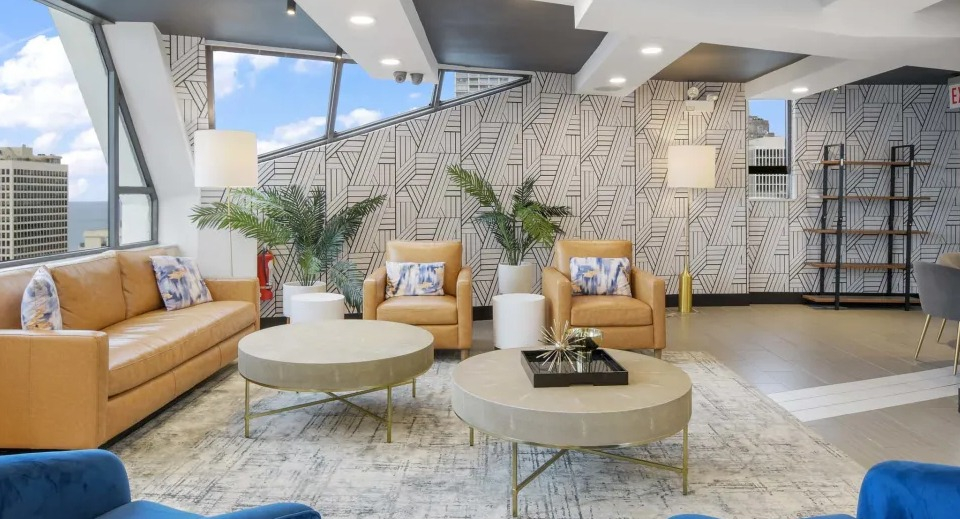 Modern resident lounge with comfortable seating, decorative wallpaper, and a cozy reading corner at Two East Oak in Chicago