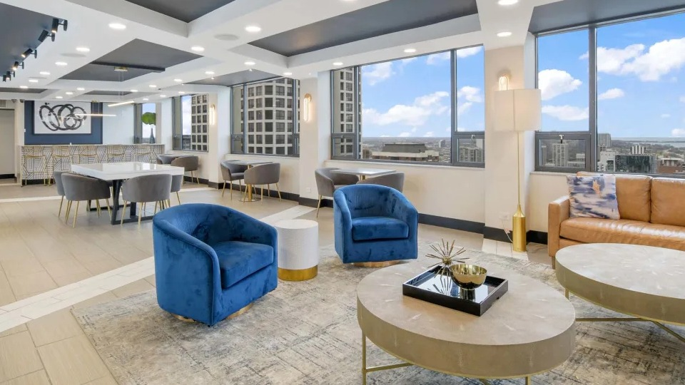 Contemporary resident lounge featuring comfortable seating, a dining area, and large windows with city views at Two East Oak in Chicago