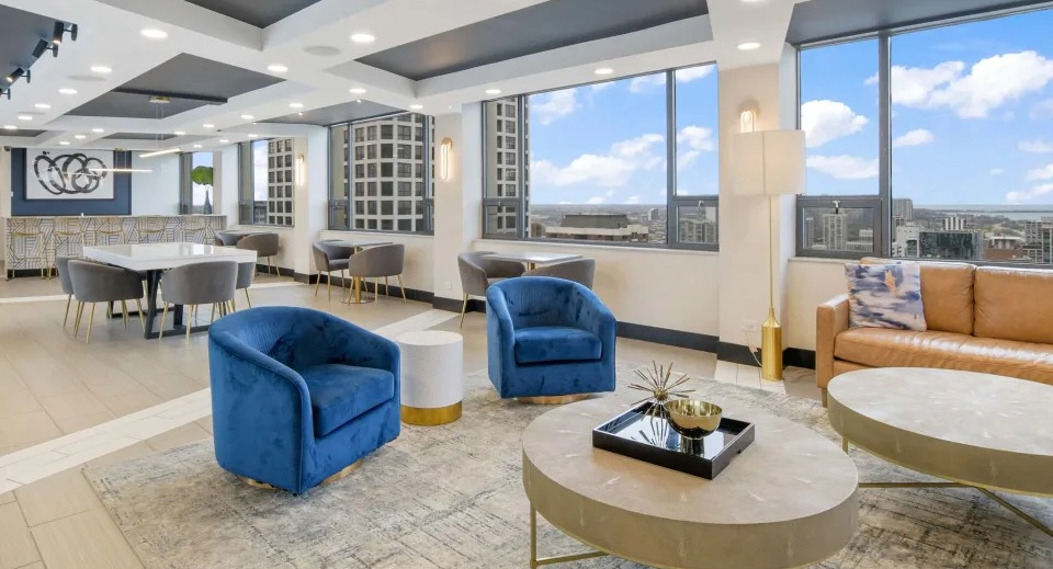 Contemporary resident lounge featuring comfortable seating, a dining area, and large windows with city views at Two East Oak in Chicago