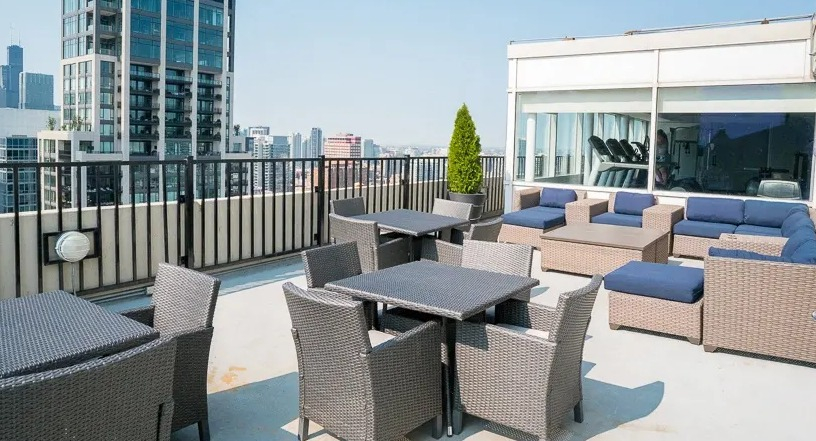 Spacious rooftop patio with various seating areas, outdoor dining tables, and expansive city views at Two East Oak in Chicago