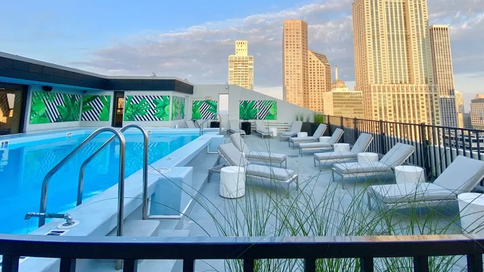 Inviting rooftop swimming pool with lounge chairs, featuring stunning views of the city skyline at Two East Oak in Chicago