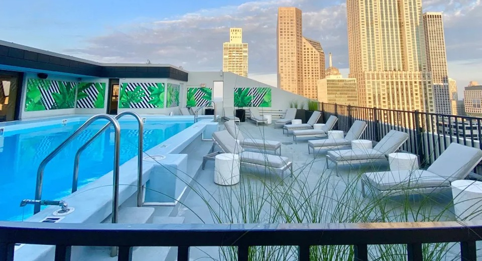 Inviting rooftop swimming pool with lounge chairs, featuring stunning views of the city skyline at Two East Oak in Chicago