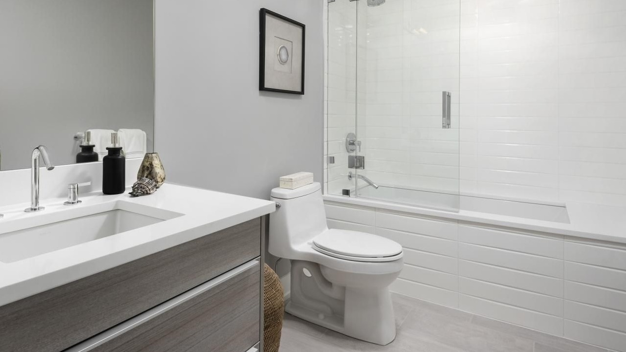 Modern bathroom with sleek fixtures, a floating vanity, white tiles, and a spacious shower-tub combo at Two West apartments in Chicago