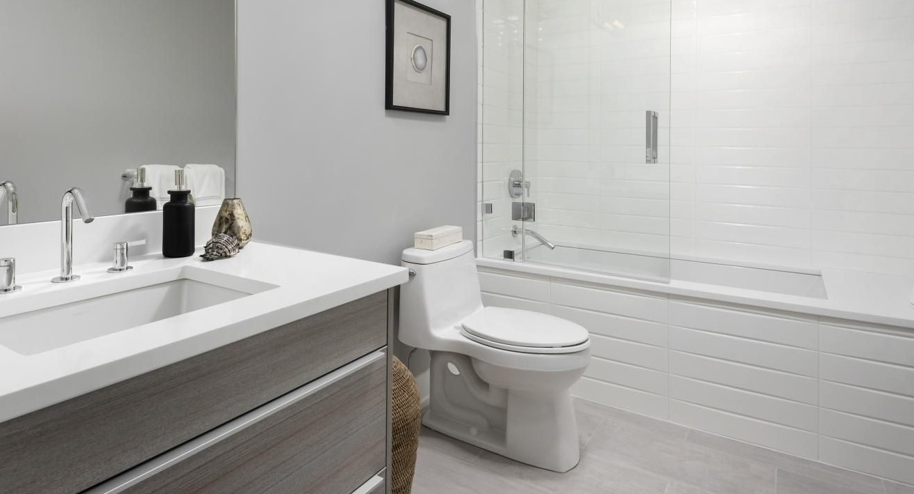 Modern bathroom with sleek fixtures, a floating vanity, white tiles, and a spacious shower-tub combo at Two West apartments in Chicago