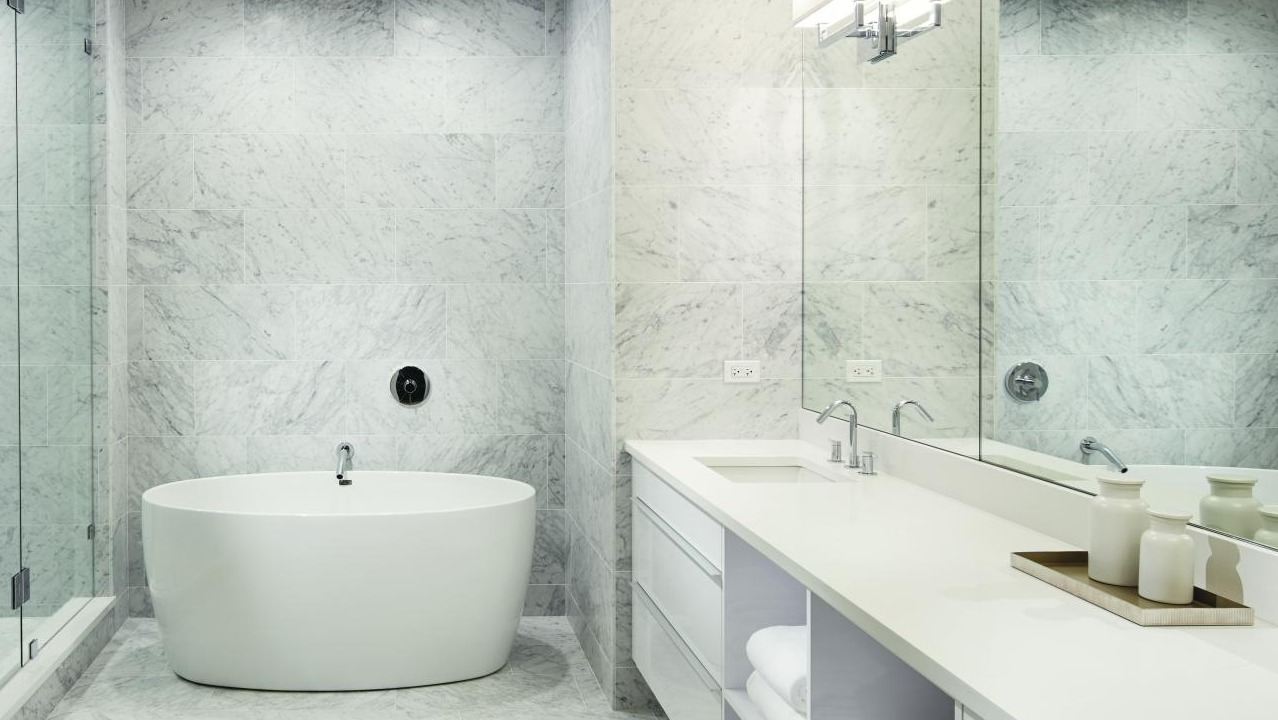 Luxurious spa-like bathroom with a freestanding tub, large vanity, and pristine white marble tiles at Two West apartments in Chicago
