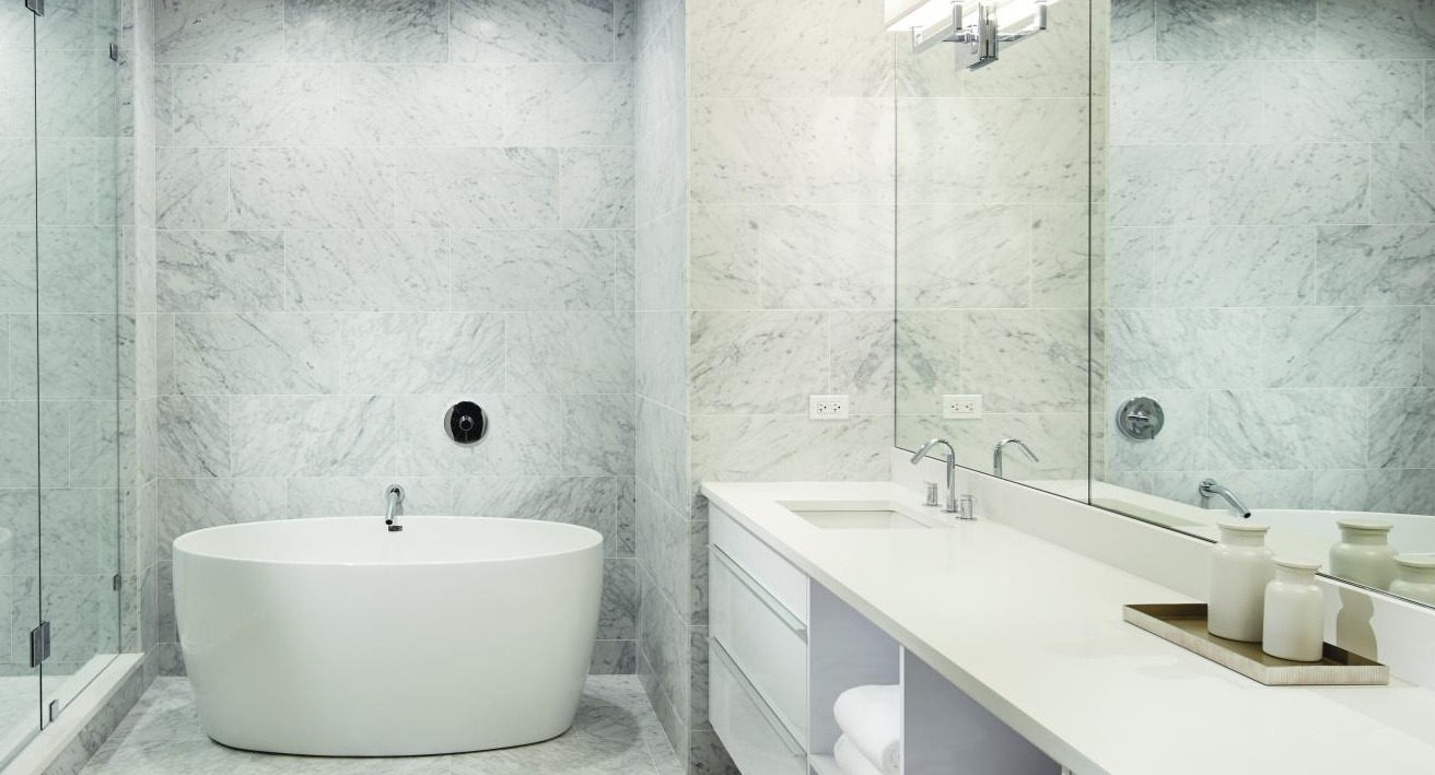Luxurious spa-like bathroom with a freestanding tub, large vanity, and pristine white marble tiles at Two West apartments in Chicago