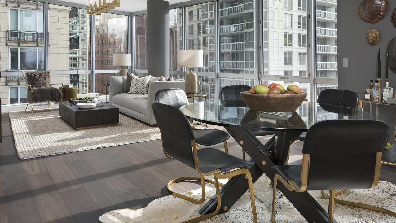 Modern open-plan dining and living room with floor-to-ceiling windows, dark wood floors, and stylish furnishings at Two West, Chicago