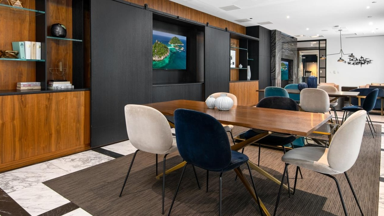 Elegant dining and lounge area with a large communal table, stylish chairs, and artistic shelving, perfect for social gatherings at Two West apartments in Chicago