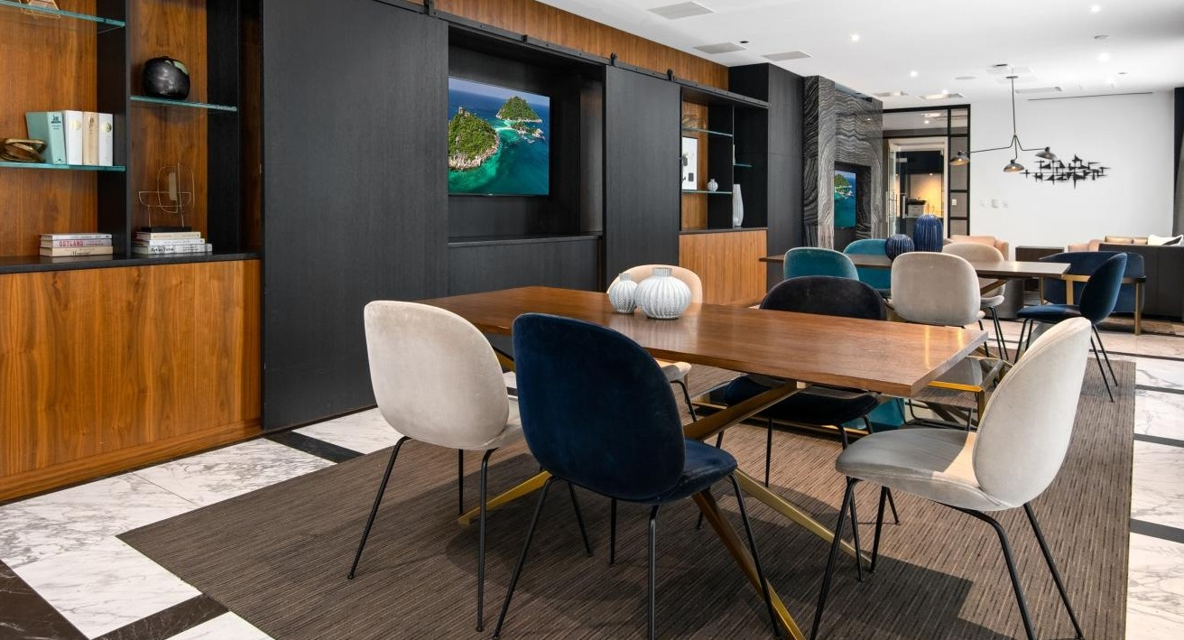 Elegant dining and lounge area with a large communal table, stylish chairs, and artistic shelving, perfect for social gatherings at Two West apartments in Chicago