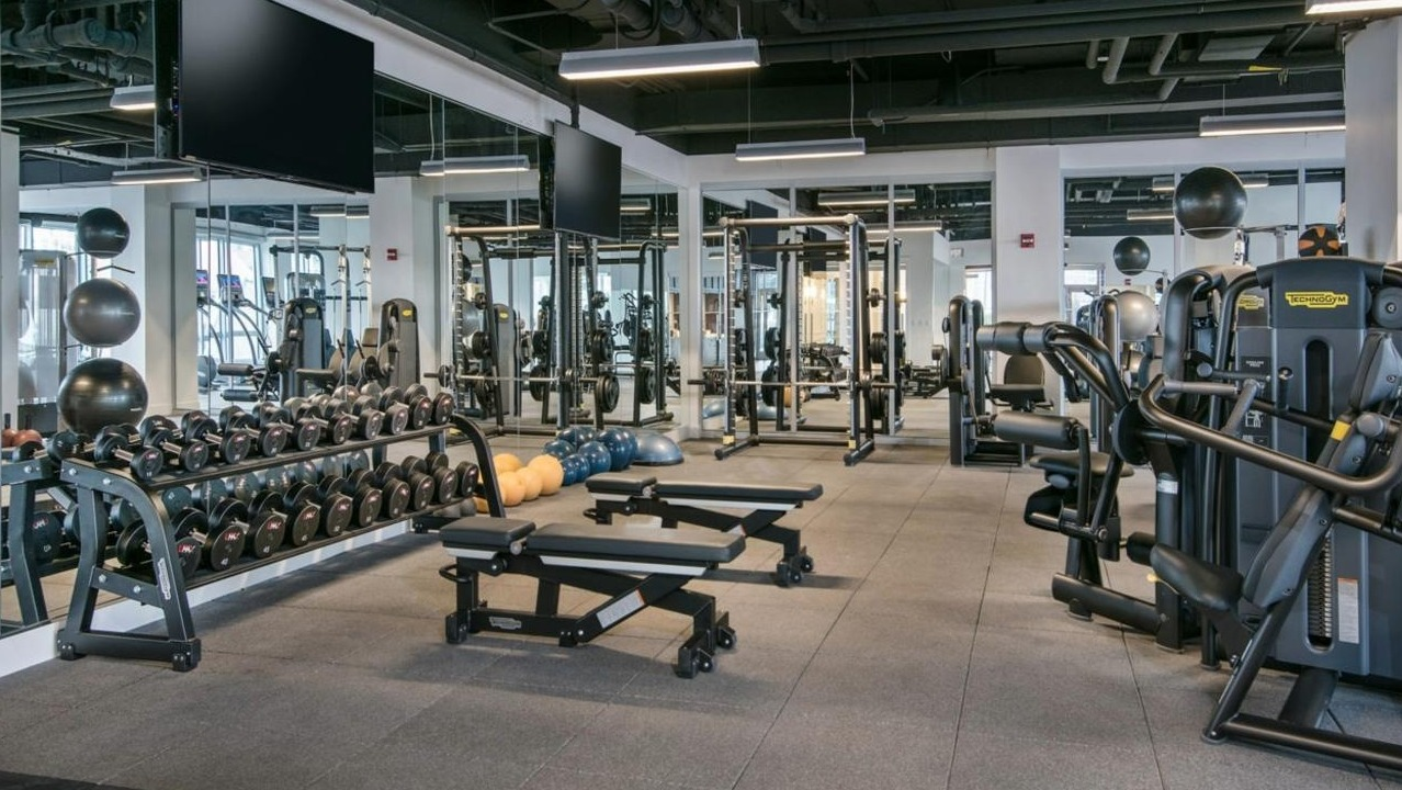 Expansive fitness center equipped with a wide range of free weights, weight machines, and ample space for strength training at Two West apartments in Chicago