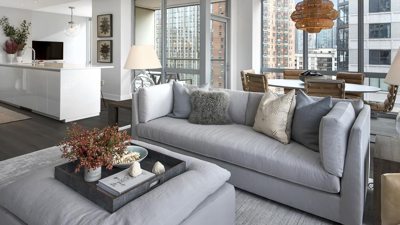 Bright and airy open-concept living and dining area with comfortable grey seating and city views at Two West apartments in Chicago