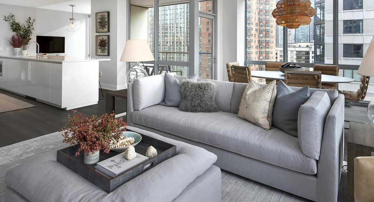 Bright and airy open-concept living and dining area with comfortable grey seating and city views at Two West apartments in Chicago
