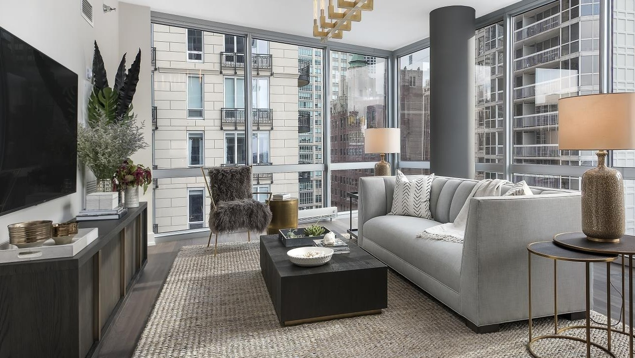 Chic living room featuring a grey sofa, dark coffee table, and stylish metallic accents, overlooking city views at Two West, Chicago
