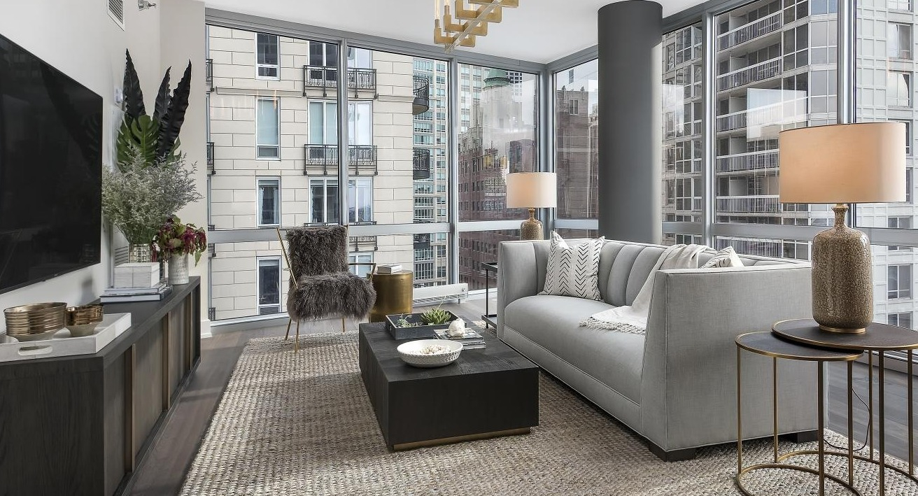 Chic living room featuring a grey sofa, dark coffee table, and stylish metallic accents, overlooking city views at Two West, Chicago