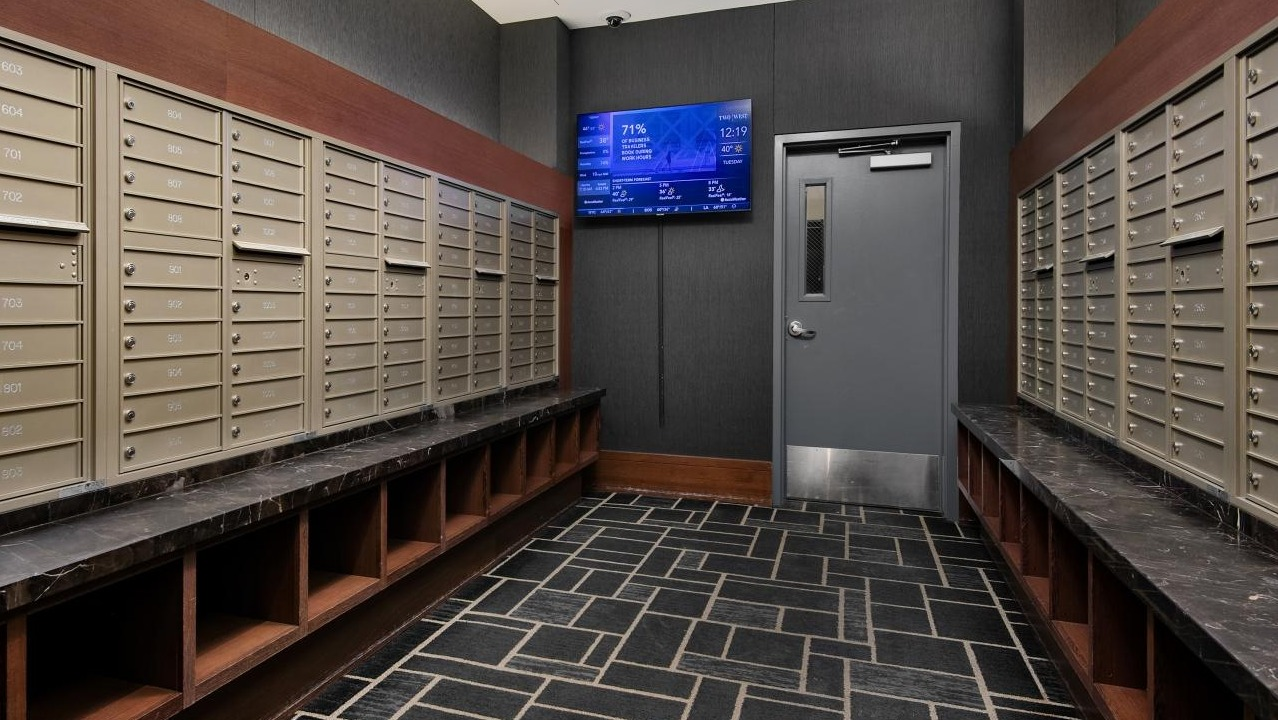 Secure and organized mailroom with numerous mailboxes and a digital display, providing convenience at Two West apartments in Chicago