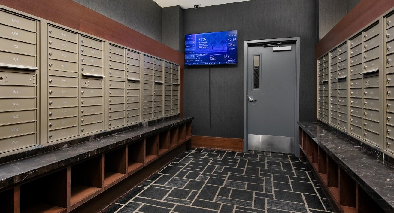 Secure and organized mailroom with numerous mailboxes and a digital display, providing convenience at Two West apartments in Chicago