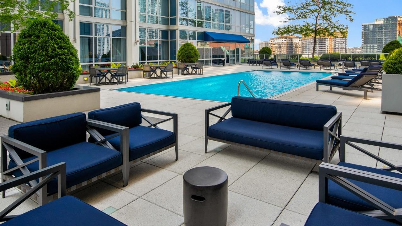 Outdoor pool deck with blue lounge chairs and seating areas, offering a luxurious amenity at Two West apartments in Chicago