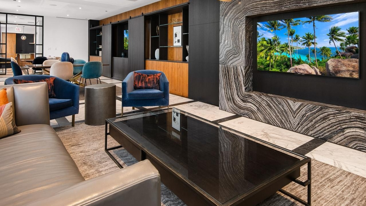 Contemporary resident lounge with comfortable seating, a large television integrated into a marble wall, and stylish decor at Two West apartments in Chicago