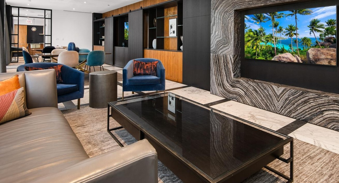 Contemporary resident lounge with comfortable seating, a large television integrated into a marble wall, and stylish decor at Two West apartments in Chicago