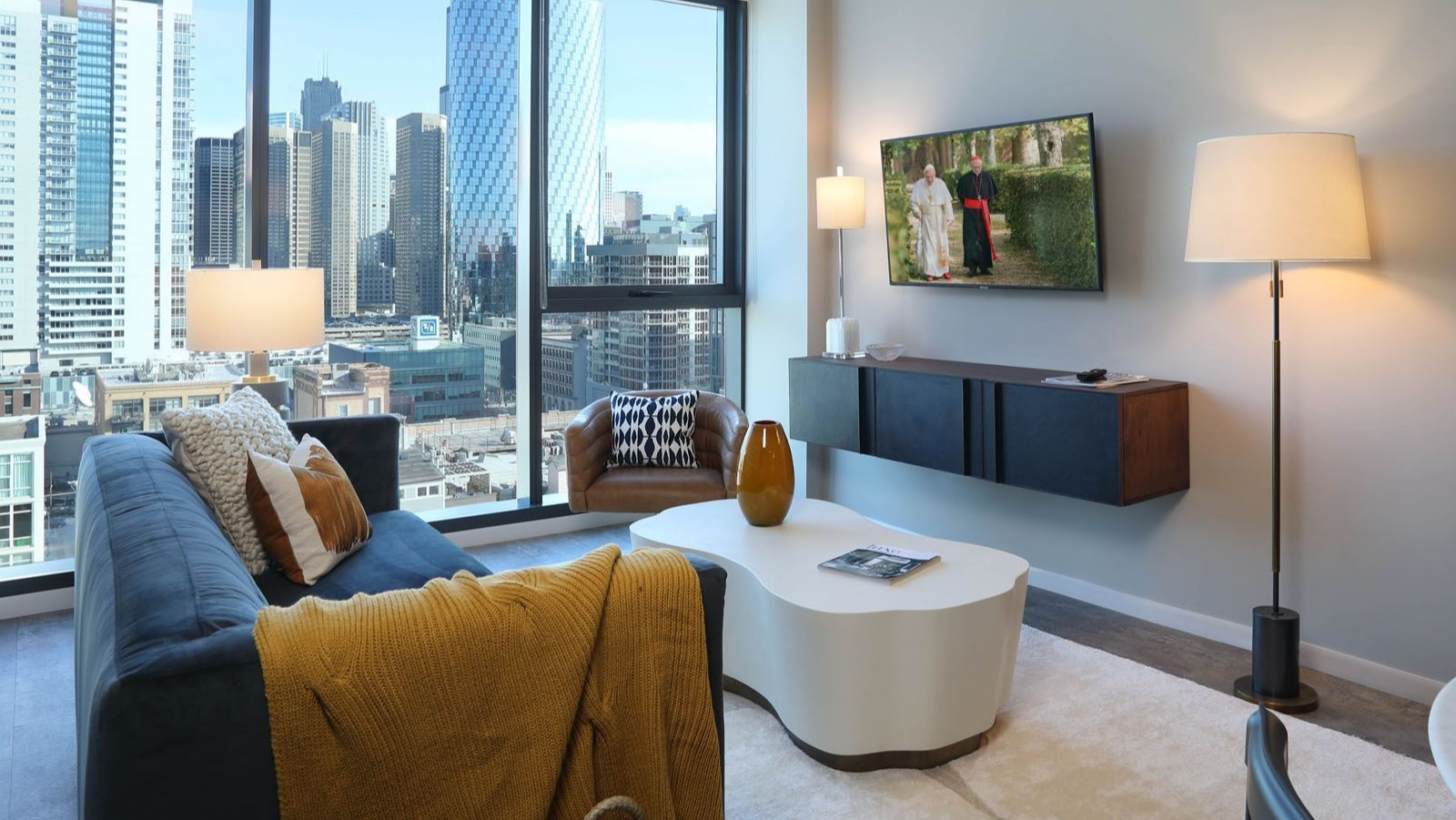 Modern living room with a comfortable sofa, stylish decor, and stunning city views from floor-to-ceiling windows at Union West, Chicago