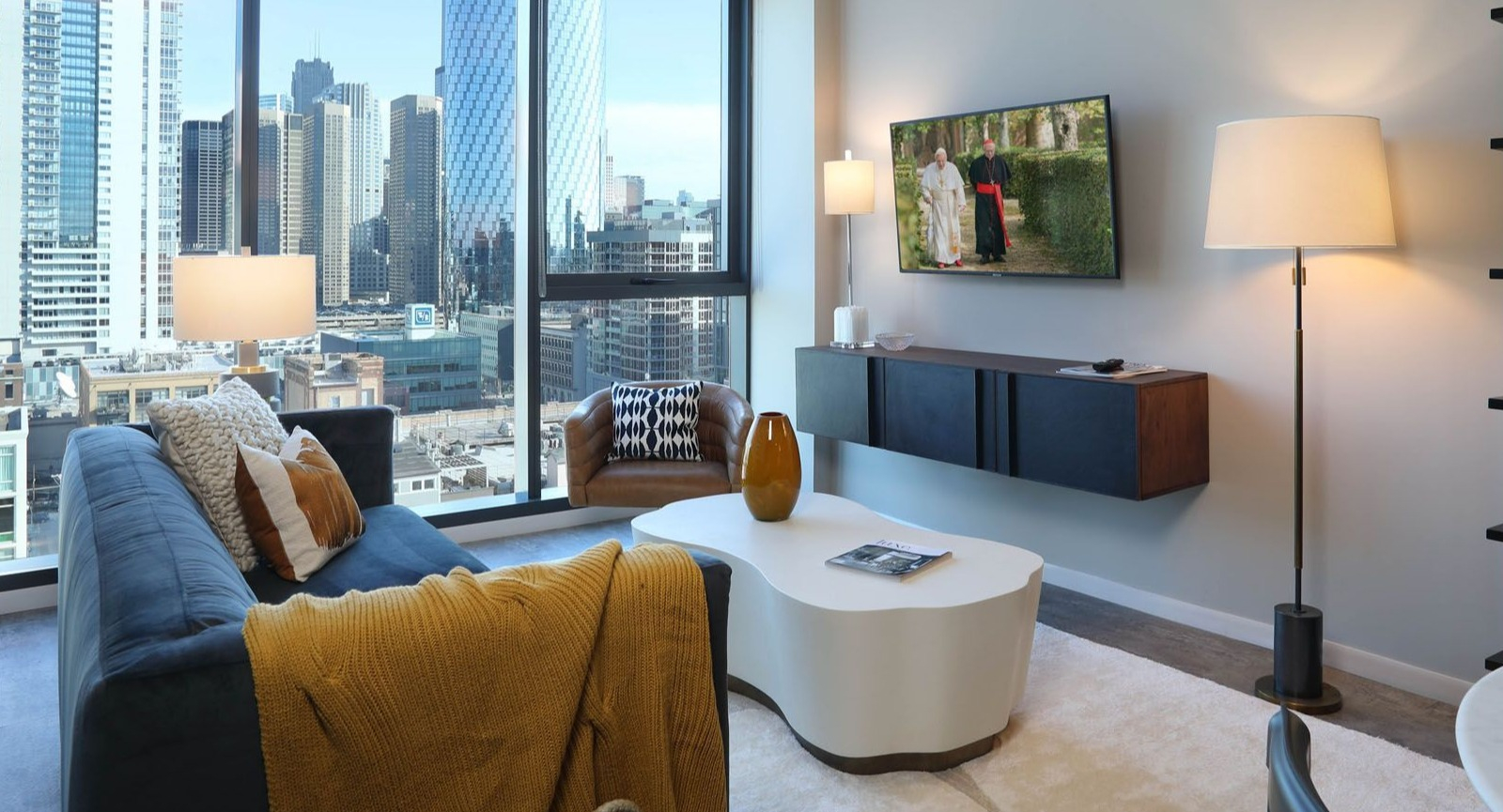 Modern living room with a comfortable sofa, stylish decor, and stunning city views from floor-to-ceiling windows at Union West, Chicago