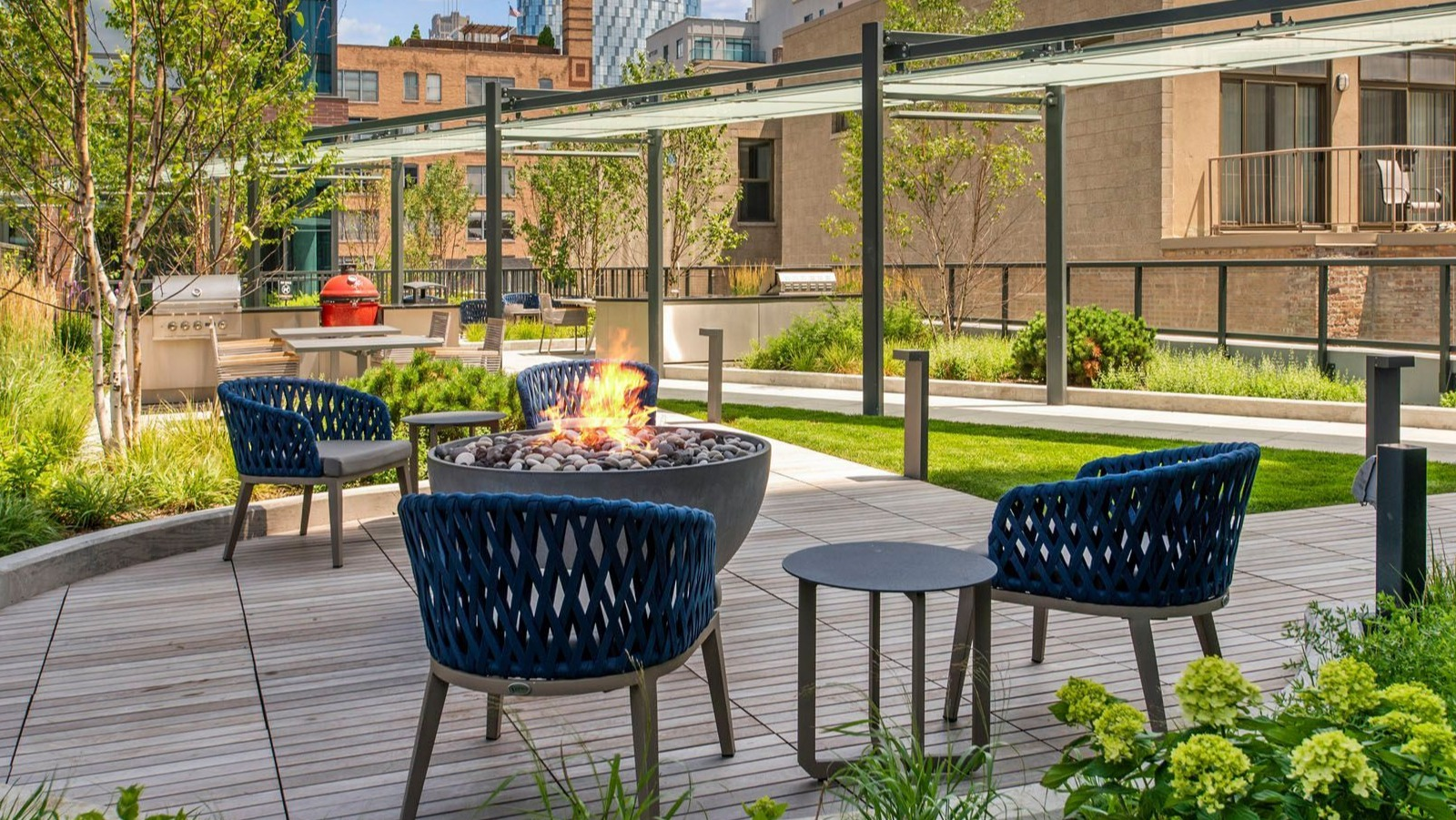 Inviting outdoor lounge area with a fire pit, comfortable seating, and lush landscaping at Union West apartments in Chicago