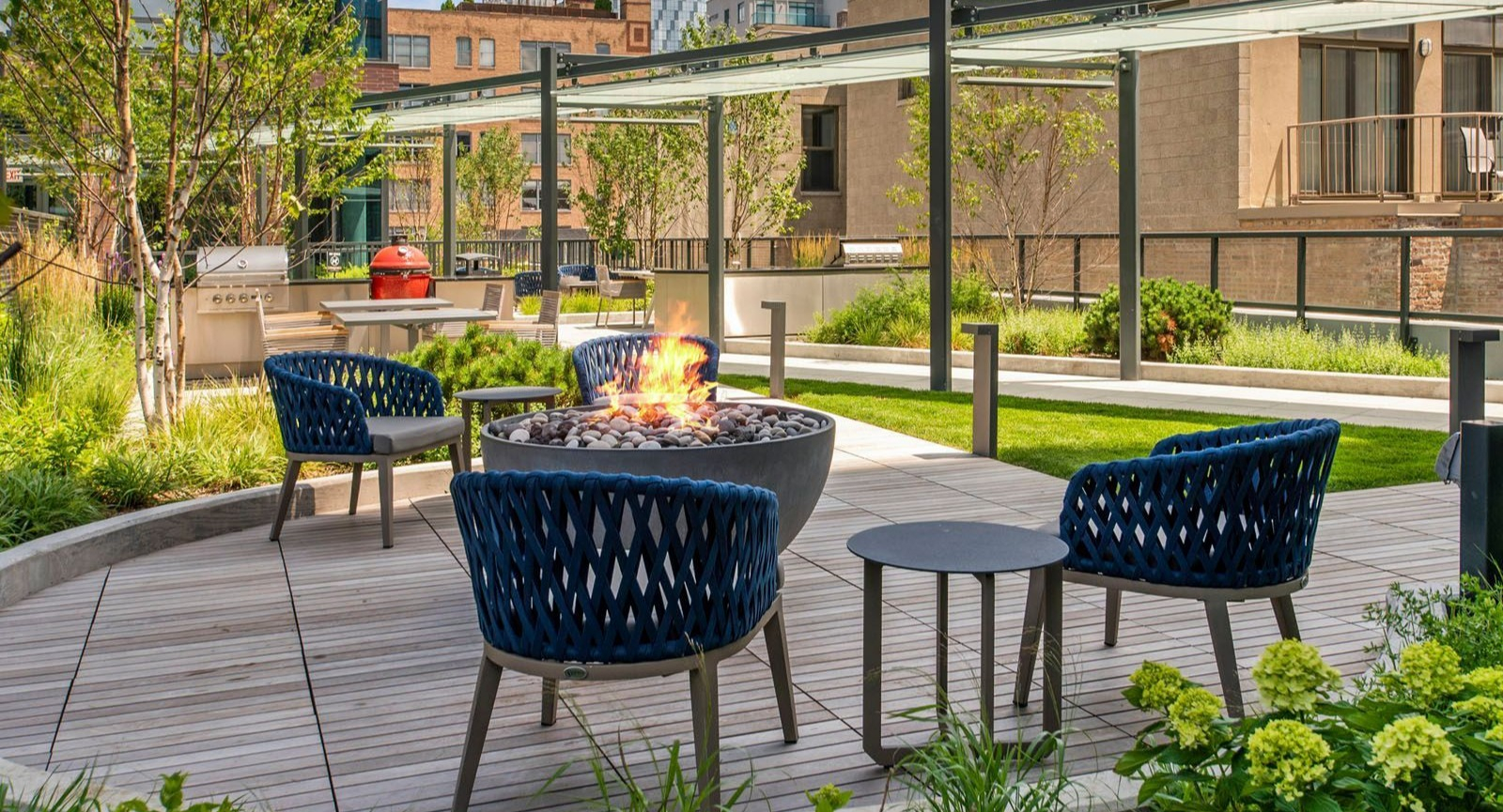 Inviting outdoor lounge area with a fire pit, comfortable seating, and lush landscaping at Union West apartments in Chicago