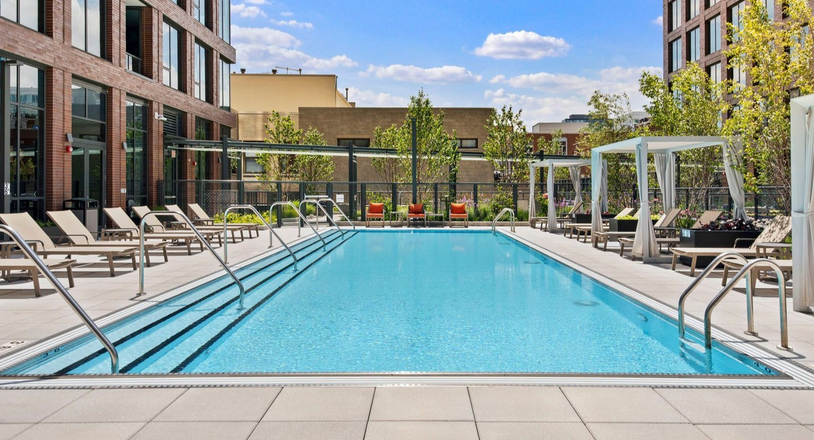 Sparkling outdoor swimming pool surrounded by lounge chairs and cabanas, ideal for relaxation at Union West apartments in Chicago