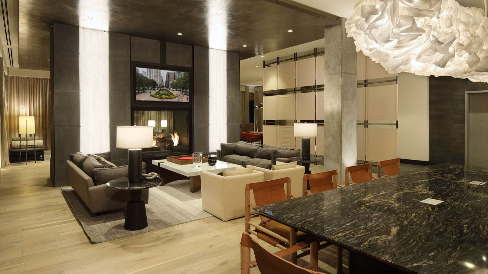 Spacious resident lounge with diverse seating areas, a long communal table, and unique lighting fixtures at Union West, Chicago