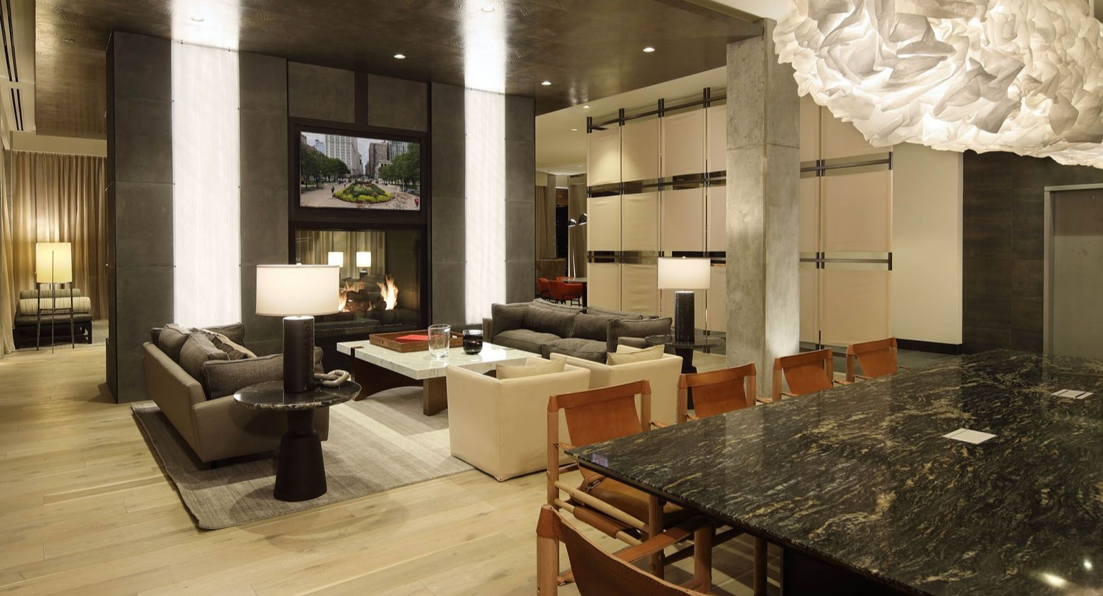 Spacious resident lounge with diverse seating areas, a long communal table, and unique lighting fixtures at Union West, Chicago