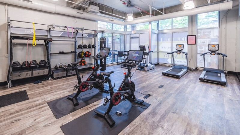 Well-equipped fitness center with various cardio machines, weight racks, and modern exercise bikes at Wells Place, Chicago