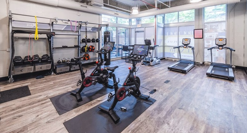 Well-equipped fitness center with various cardio machines, weight racks, and modern exercise bikes at Wells Place, Chicago