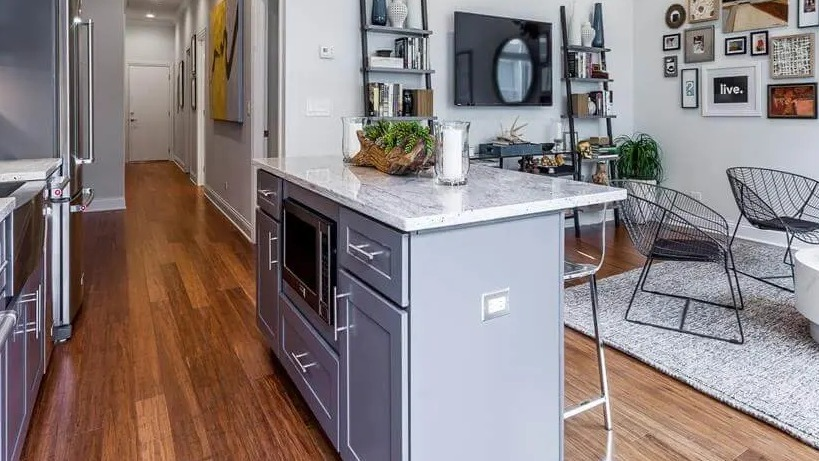 View from the kitchen island extending into a vibrant living area and a long hallway at Wells Place Apartments, Chicago