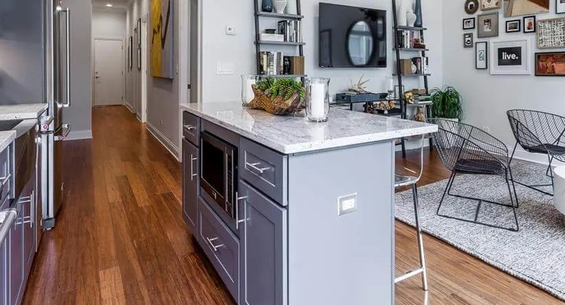View from the kitchen island extending into a vibrant living area and a long hallway at Wells Place Apartments, Chicago