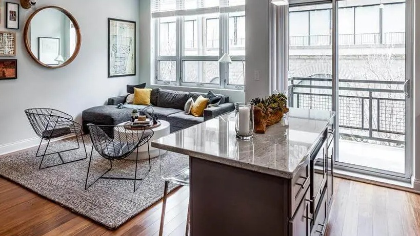 Open-concept living room with a comfortable sectional sofa, modern decor, and large windows at Wells Place Apartments in Chicago
