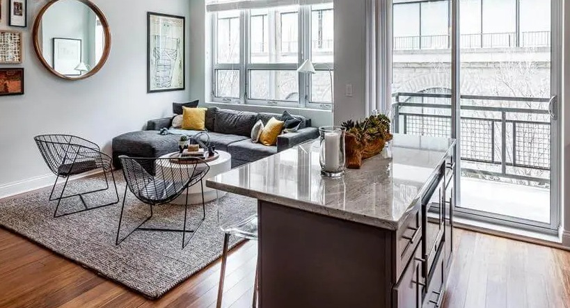 Open-concept living room with a comfortable sectional sofa, modern decor, and large windows at Wells Place Apartments in Chicago
