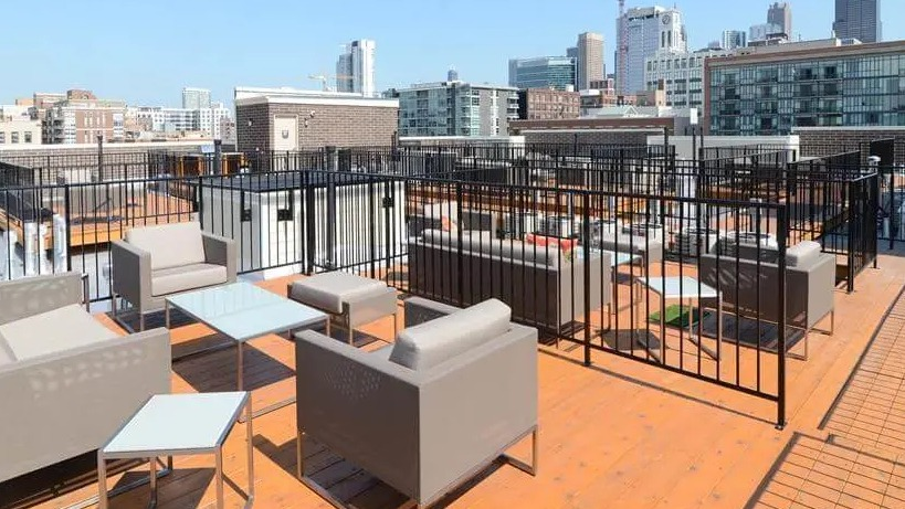 Expansive rooftop lounge area with modern outdoor furniture and breathtaking Chicago city skyline views at Wells Place, Chicago