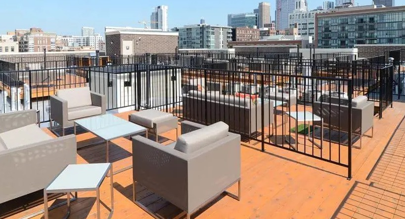 Expansive rooftop lounge area with modern outdoor furniture and breathtaking Chicago city skyline views at Wells Place, Chicago