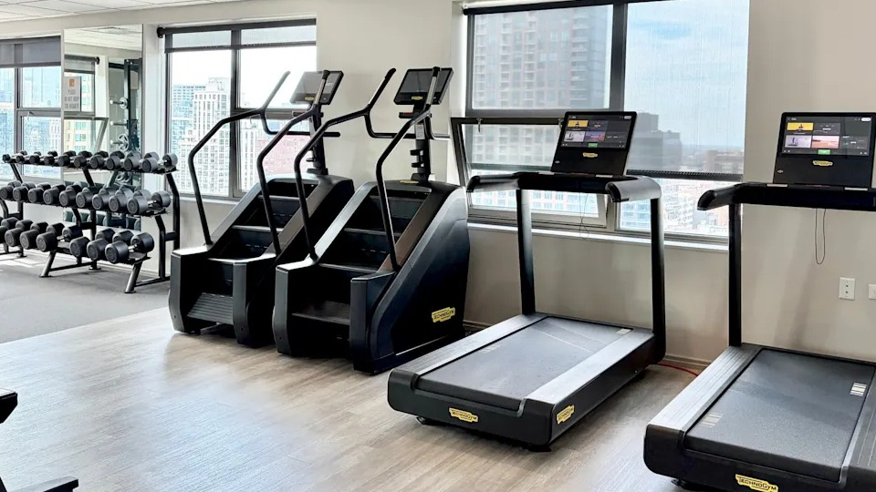 Dedicated cardio room within the fitness center, featuring treadmills, stair climbers, and views of the city at West77, Chicago