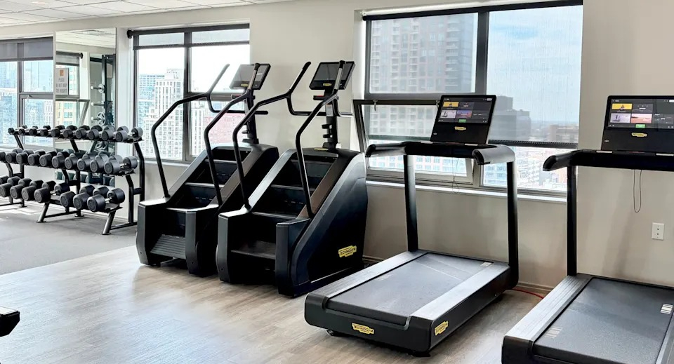 Dedicated cardio room within the fitness center, featuring treadmills, stair climbers, and views of the city at West77, Chicago